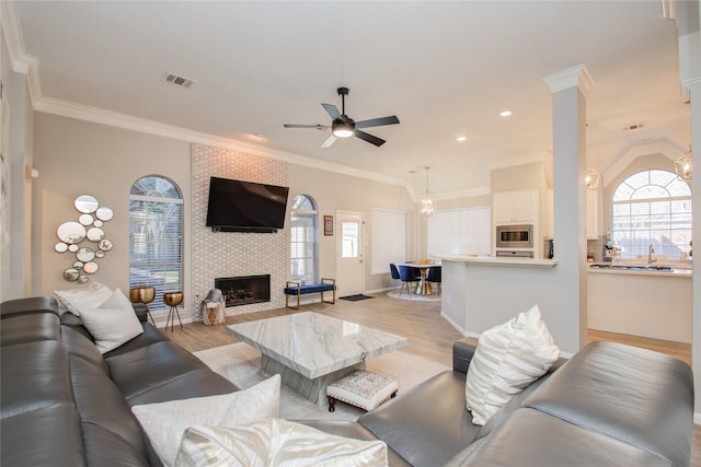 living room featuring light hardwood / wood-style flooring, crown molding, and a fireplace