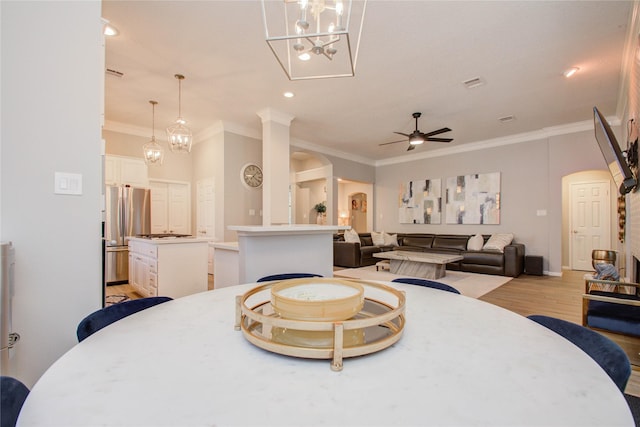 dining room with crown molding, ceiling fan with notable chandelier, and light hardwood / wood-style floors