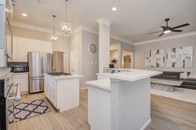 kitchen featuring white cabinetry, light hardwood / wood-style floors, stainless steel appliances, hanging light fixtures, and a kitchen island