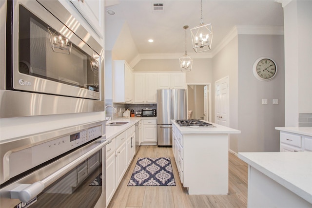 kitchen featuring pendant lighting, white cabinets, a kitchen island, stainless steel appliances, and sink