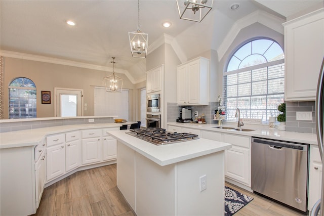 kitchen featuring appliances with stainless steel finishes, decorative backsplash, a kitchen island, white cabinets, and sink