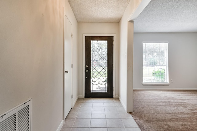 tiled entrance foyer with a textured ceiling and a healthy amount of sunlight