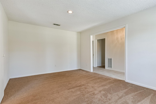 carpeted empty room featuring a textured ceiling