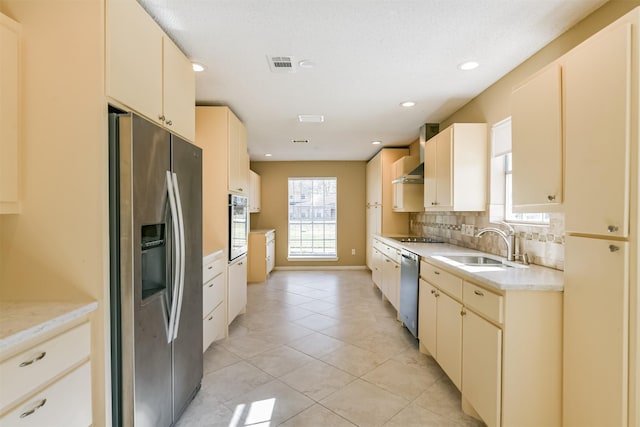 kitchen with wall chimney exhaust hood, stainless steel appliances, decorative backsplash, sink, and light tile patterned flooring