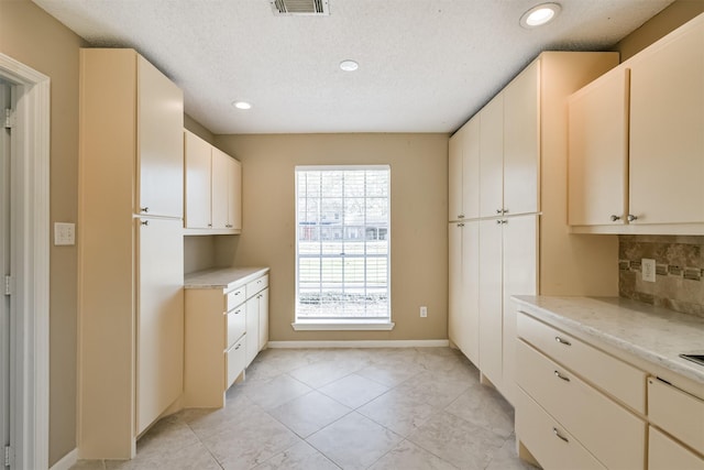 kitchen featuring backsplash, light tile patterned floors, and a textured ceiling