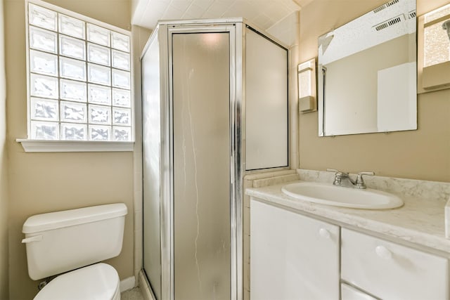 bathroom featuring a shower with shower door, toilet, and vanity