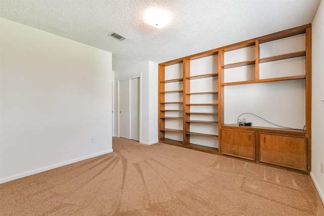 interior space featuring a textured ceiling and light colored carpet