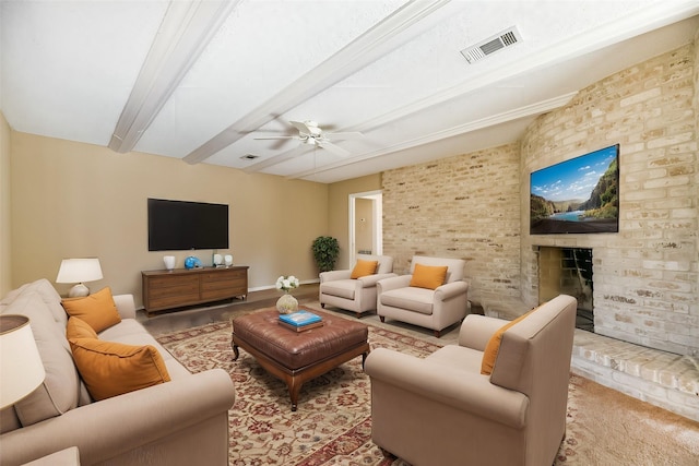 living room with ceiling fan, beamed ceiling, and a fireplace