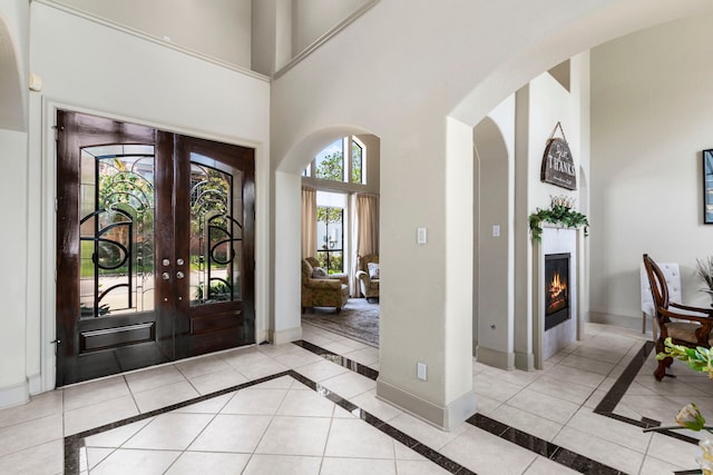 4 Mariners Ln, Kemah, TX 77565 - foyer with inlaid floor details, a towering ceiling, arched walkways, french doors, and a glass covered fireplace