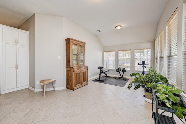 workout area with light tile patterned floors and vaulted ceiling