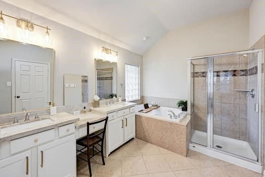 bathroom featuring vanity, independent shower and bath, lofted ceiling, and tile patterned flooring