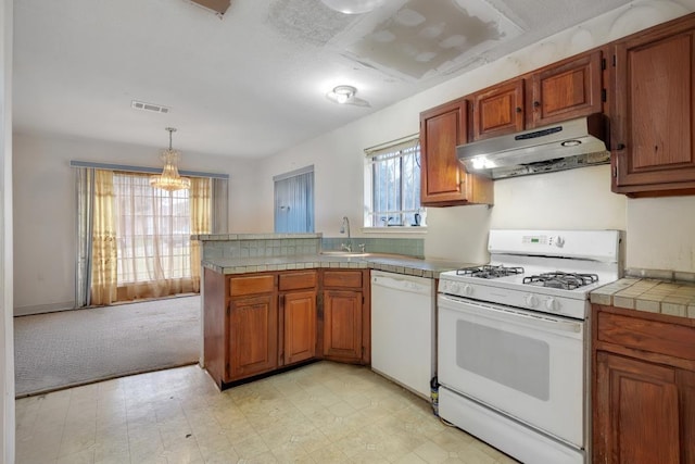 kitchen with light carpet, kitchen peninsula, decorative light fixtures, white appliances, and sink