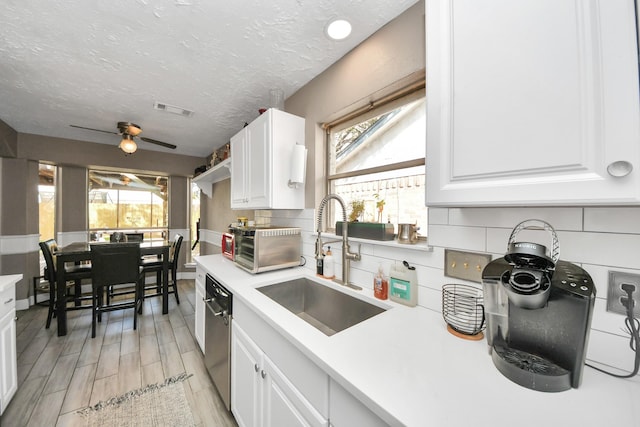 kitchen featuring sink, white cabinetry, stainless steel dishwasher, and a textured ceiling