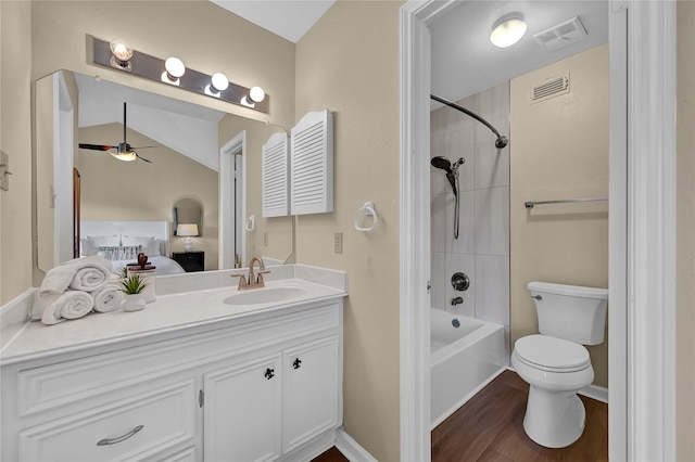 full bathroom featuring toilet, tiled shower / bath combo, hardwood / wood-style flooring, ceiling fan, and vanity