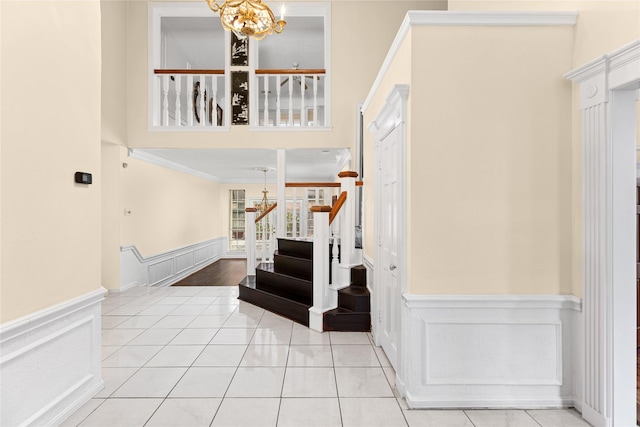 foyer featuring an inviting chandelier, light tile patterned floors, and ornamental molding