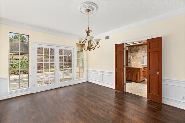 unfurnished dining area with a textured ceiling, french doors, an inviting chandelier, hardwood / wood-style flooring, and crown molding