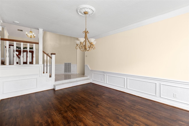 empty room with a notable chandelier, crown molding, a textured ceiling, and wood-type flooring