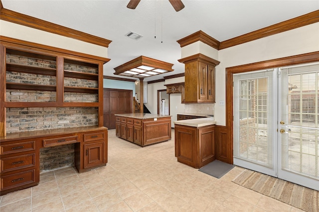 kitchen featuring tasteful backsplash, a kitchen island, built in desk, ornamental molding, and ceiling fan