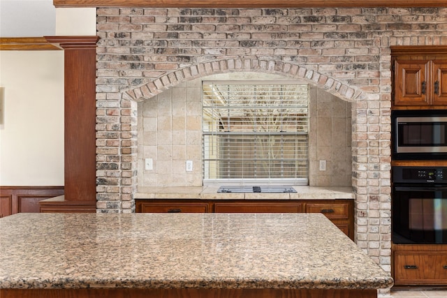 kitchen with light stone counters, decorative backsplash, black appliances, and a kitchen island