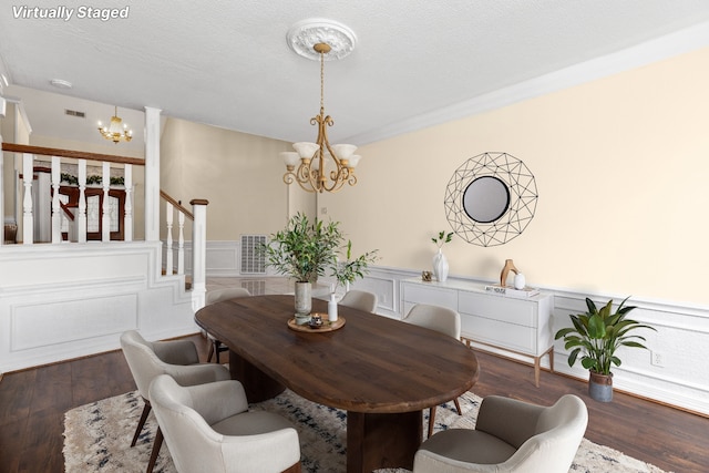 dining area with a textured ceiling, dark hardwood / wood-style floors, crown molding, and an inviting chandelier