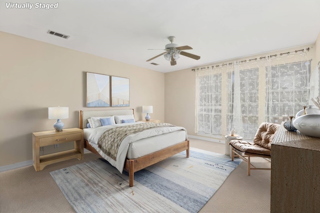 bedroom with ceiling fan, light carpet, and multiple windows