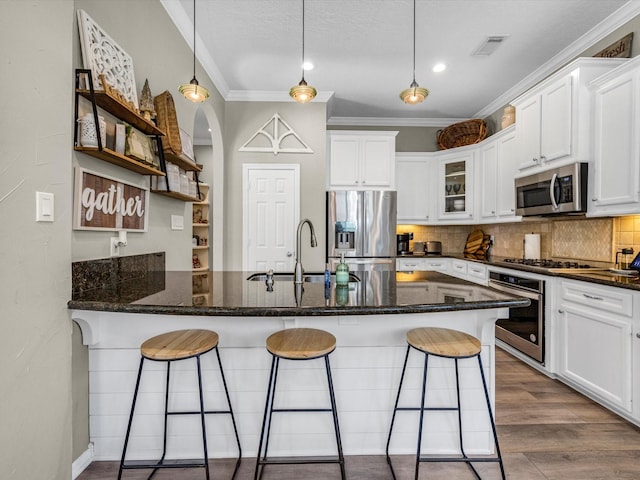 kitchen with crown molding, white cabinets, stainless steel appliances, and a breakfast bar area