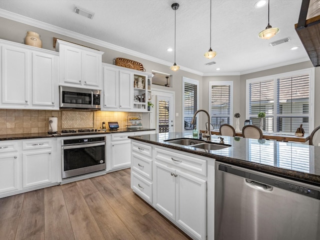 kitchen featuring pendant lighting, decorative backsplash, sink, stainless steel appliances, and white cabinets