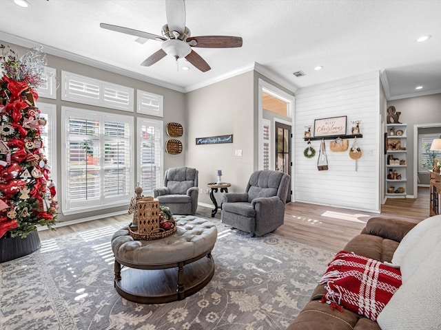 living room with ceiling fan, ornamental molding, and light hardwood / wood-style flooring