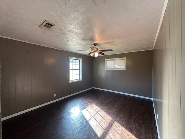 empty room featuring ceiling fan, wood walls, a textured ceiling, and dark hardwood / wood-style flooring