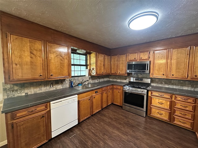 kitchen with dark wood-type flooring, sink, appliances with stainless steel finishes, and tasteful backsplash