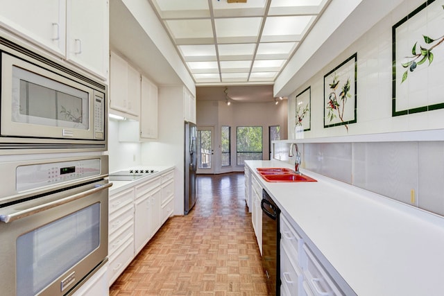 kitchen featuring sink, black appliances, white cabinets, and light parquet flooring