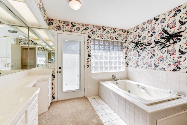 bathroom with tiled bath, vanity, and tile patterned flooring