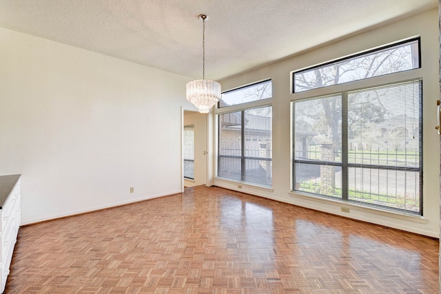 unfurnished dining area with light parquet floors, an inviting chandelier, and a textured ceiling