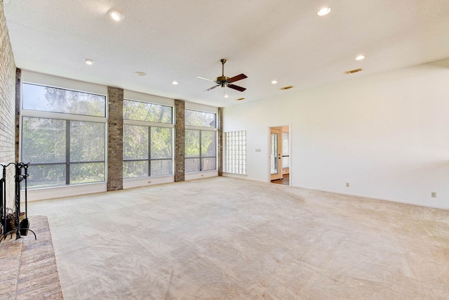 unfurnished living room featuring a fireplace, light colored carpet, a high ceiling, and ceiling fan