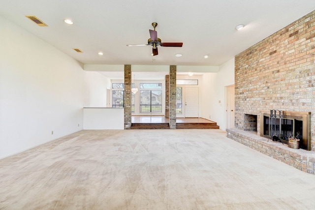 unfurnished living room featuring a brick fireplace, light colored carpet, and ceiling fan