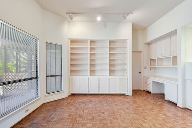 unfurnished living room featuring light parquet floors and built in desk