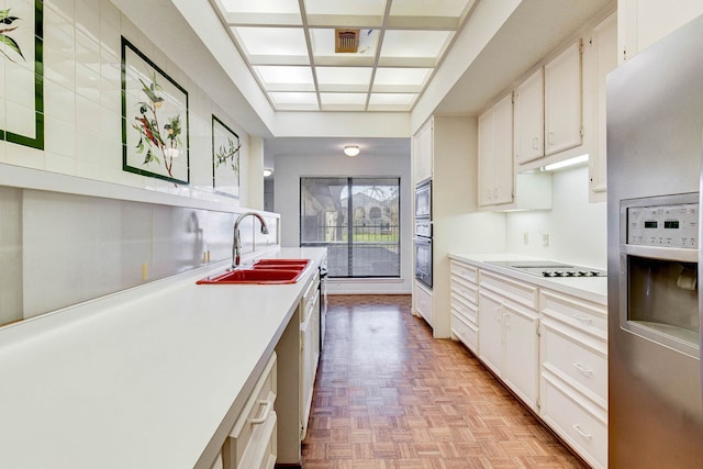 kitchen with white cabinets, appliances with stainless steel finishes, light parquet floors, and sink