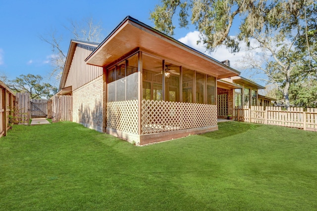 rear view of property featuring ceiling fan, a lawn, and a sunroom