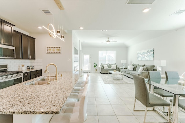 kitchen with dark brown cabinets, sink, a kitchen bar, a center island with sink, and stainless steel appliances