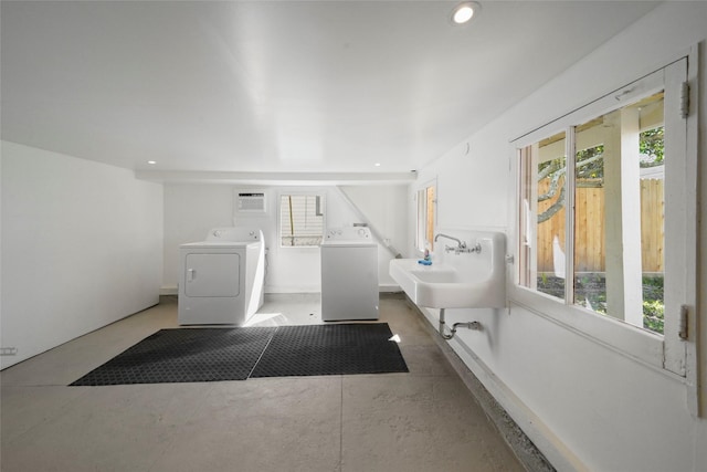 washroom with sink, a wall unit AC, independent washer and dryer, and a healthy amount of sunlight