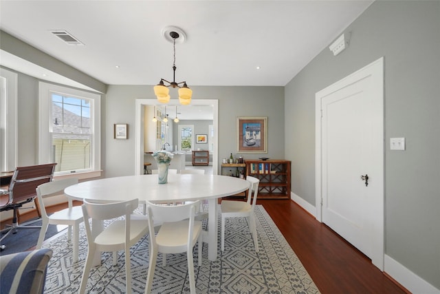 dining area featuring dark wood-type flooring and a notable chandelier