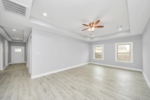 spare room with ceiling fan and a raised ceiling