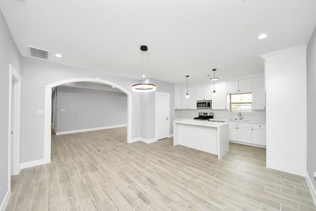 kitchen with a center island, white cabinetry, sink, pendant lighting, and stainless steel appliances