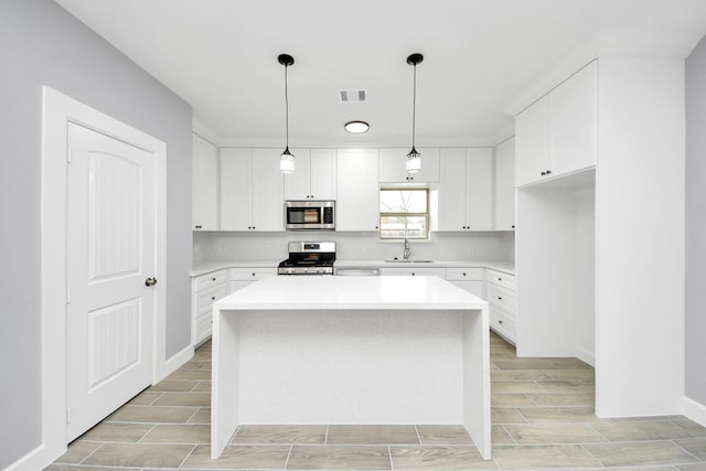 kitchen featuring sink, a center island, white cabinetry, and appliances with stainless steel finishes