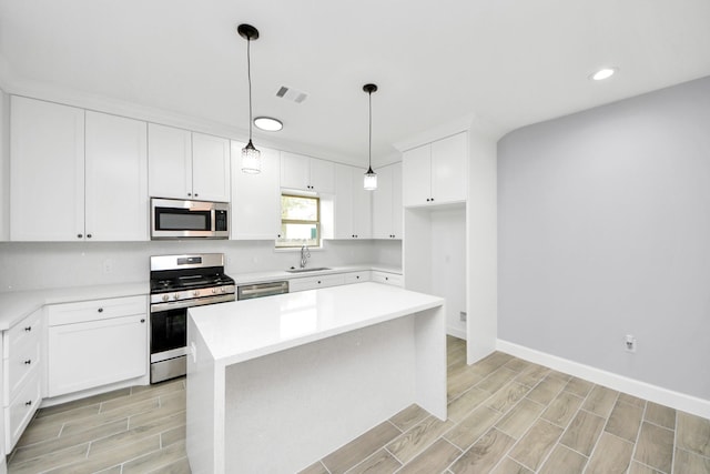 kitchen with a center island, white cabinetry, hanging light fixtures, sink, and stainless steel appliances