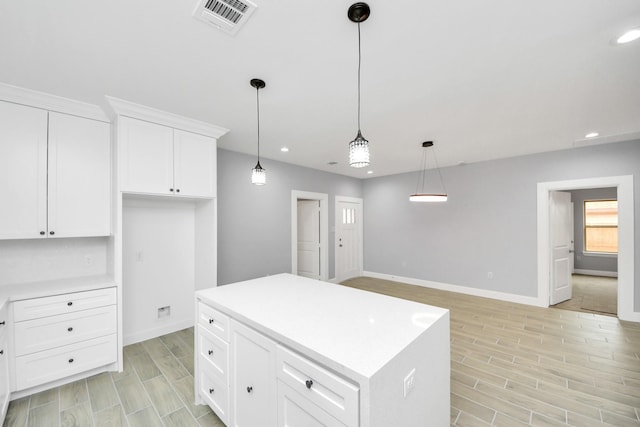 kitchen with white cabinets, a center island, and pendant lighting