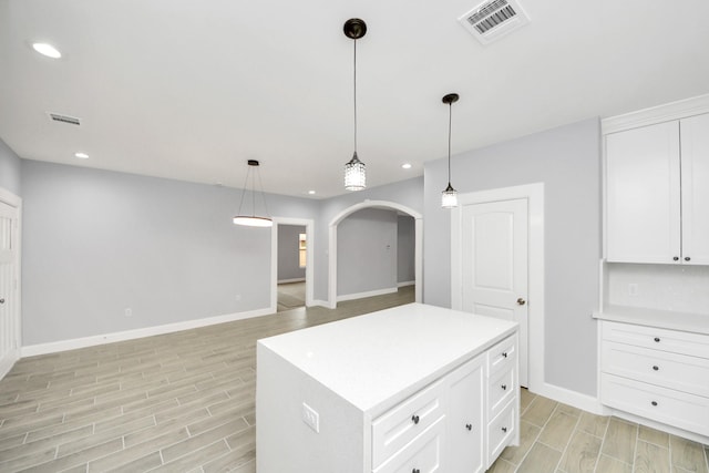 kitchen featuring decorative light fixtures, a center island, and white cabinetry