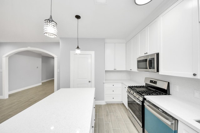 kitchen with white cabinets, hanging light fixtures, and appliances with stainless steel finishes