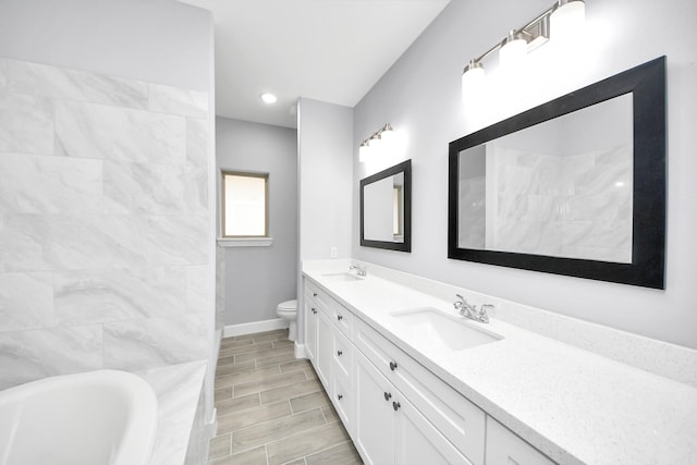 bathroom featuring toilet, a bathing tub, and vanity