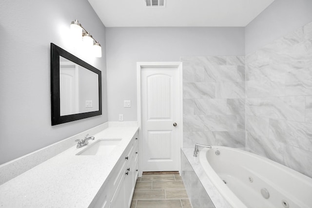 bathroom featuring vanity and tiled bath